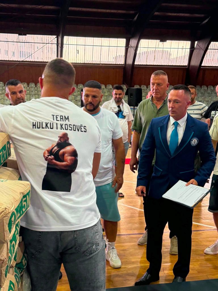 An official in a blue suit and a man in a “Team Hulku i Kosovës” top.