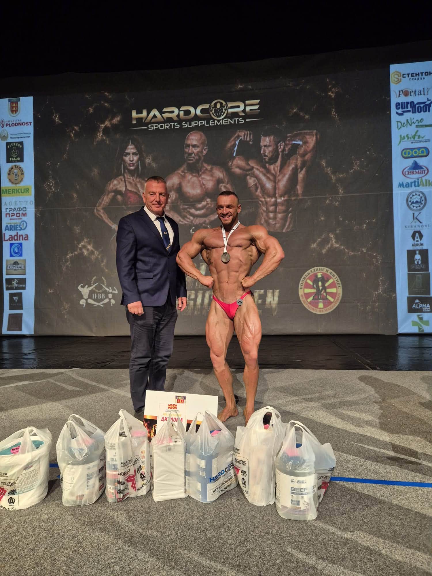 Fatlind Kërqeli me medaljen dhe çmimet në skenë, pranë një zyrtari, në Paljo Classic Open.